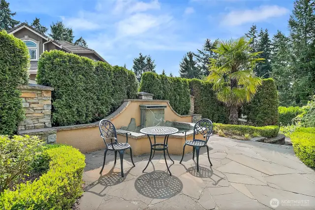 Charming fountain inspired sitting area at the front of the home offers a serene spot to relax and enjoy the beautifully landscaped surroundings.