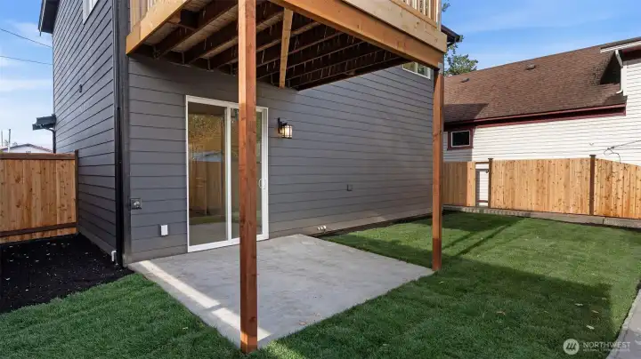 Fully fenced and landscaped backyard has covered patio.