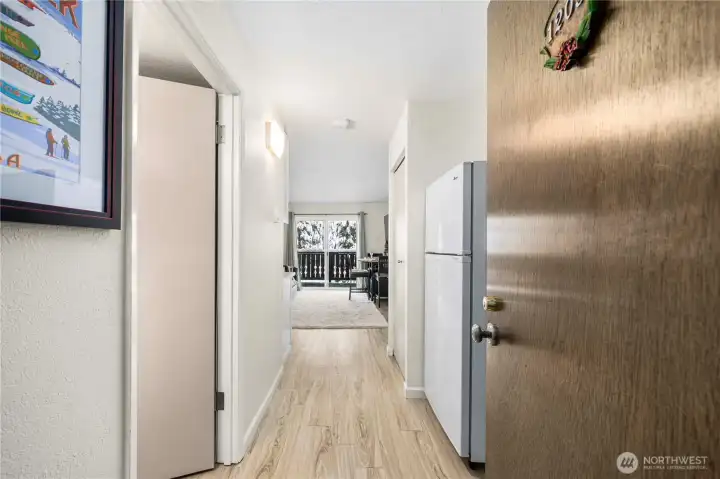 Welcoming entry hallway featuring durable LPV flooring throughout, leading into a bright and cozy living space. The thoughtful layout offers an easy flow from entry to the main living area, ideal for mountain living with space for gear and everyday comfort. Natural light draws you toward the balcony beyond—perfect for relaxing after a day on the slopes at Alpental.
