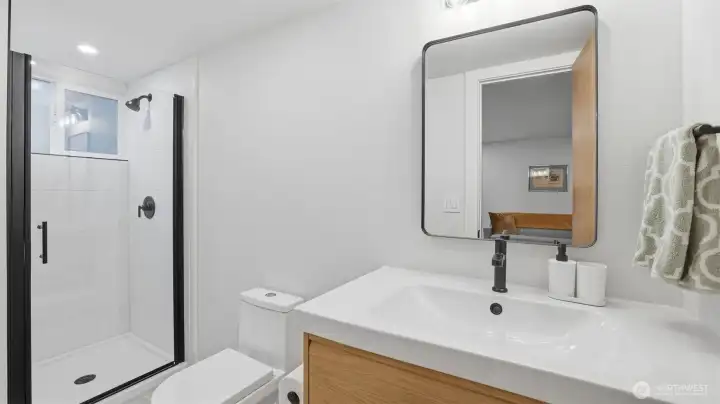 Practical lower-level 3/4 bath for guests, featuring fresh, updated finishes.