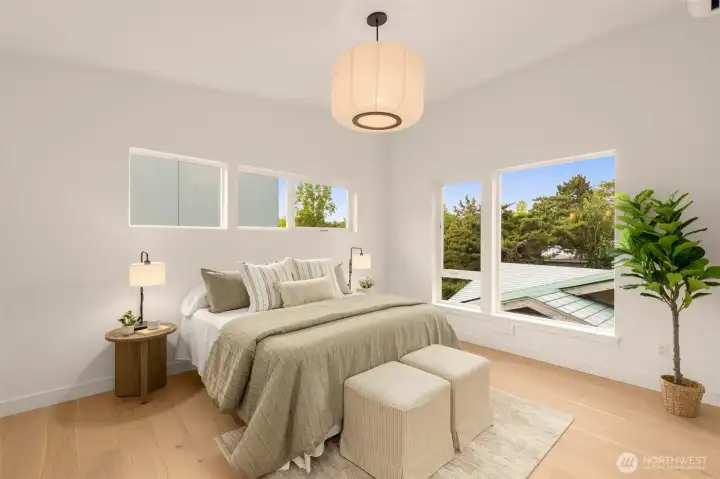 Tranquil primary bedroom with space for a king bed and a cozy reading chair. A large window brings in calming natural light.
