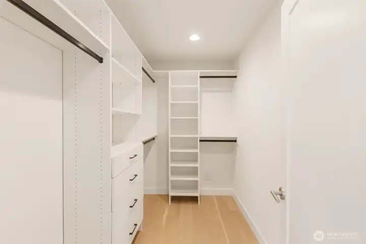 Organized living starts here with a walk in closet fitted with custom shelving, drawers, and hanging space.