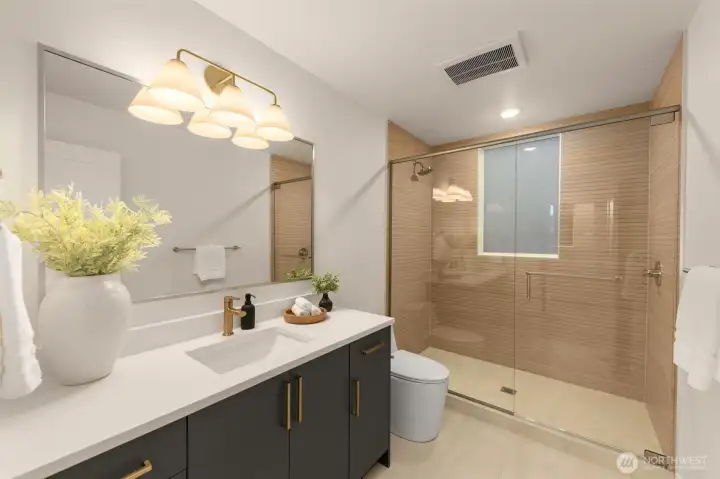 Sleek full bath showcasing a walk-in rain shower, quartz vanity, and warm accents. A thoughtfully designed retreat balancing modern luxury with everyday function.