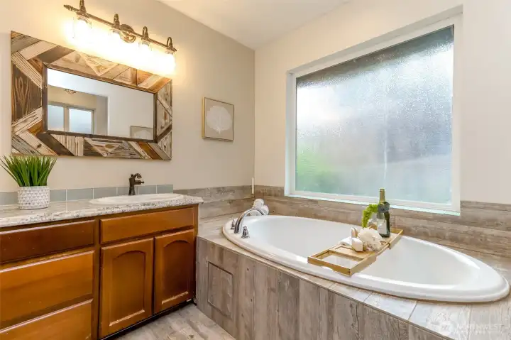 Full bathroom with shower to the right of deep soaking tub.