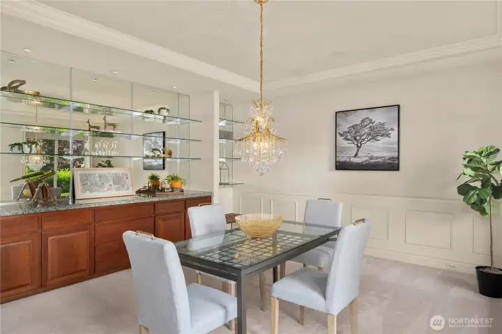 The dining room features a beautiful chandelier along with built-in glass shelving and cabinetry.