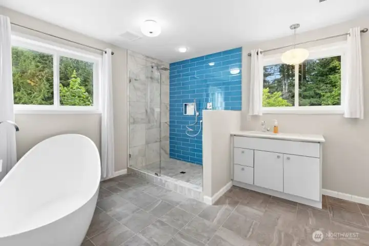 The primary suite features deck access and an updated en-suite bath with tile flooring, a tiled walk-in shower, and a separate soaking tub. The primary suite features deck access and an updated en-suite bath with tile flooring, a tiled walk-in shower, and a separate soaking tub.