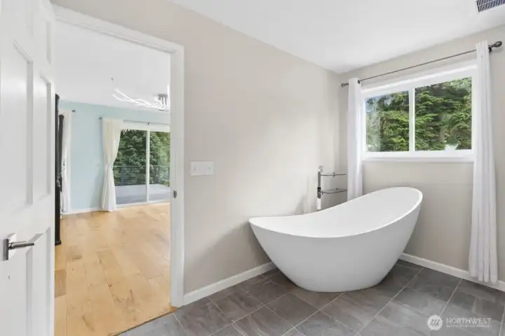 The primary suite features deck access and an updated en-suite bath with tile flooring, a tiled walk-in shower, and a separate soaking tub. The primary suite features deck access and an updated en-suite bath with tile flooring, a tiled walk-in shower, and a separate soaking tub.