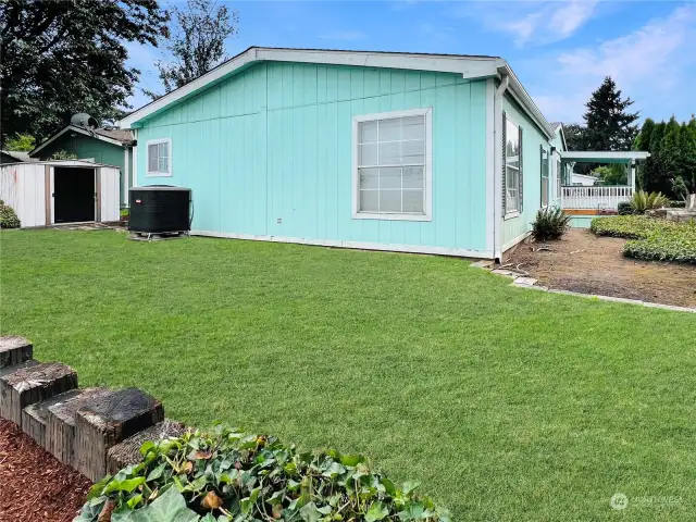 Back of home, heat pump. Storage shed stays. Grass is color enhanced.