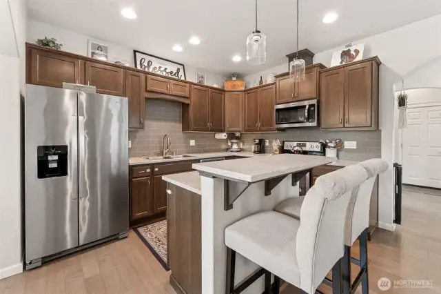Kitchen view, matching stainless steel appliances, love the island and breakfast bar, deluxe cabinetry and quartz countertops.