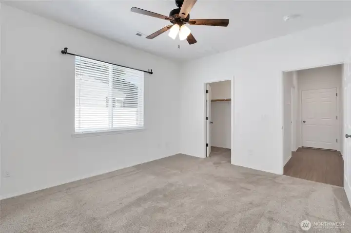 Primary bedroom with ceiling fan, natural light, and carpet flooring