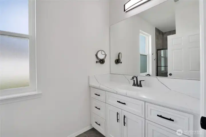 Primary bathroom with dual-sink vanity, storage, and natural light