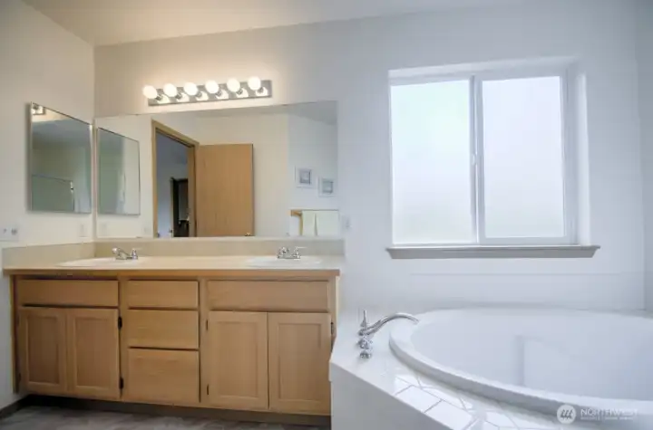 Primary bathroom with dual sink vanity a soaking tub, plus a step-in shower.