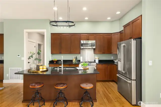 The kitchen features wood cabinetry, a breakfast bar, and everything you need to cook and gather with ease.