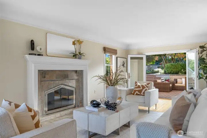 The living room features the original fireplace with gorgeous tile detail. French doors on the far end open to the back patio.