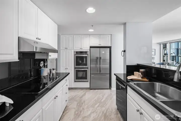 Clean lines and a sophisticated color palette define this kitchen. Enjoy the practicality of a large black granite countertop, ample storage, and a layout that flows seamlessly into the main living area.
