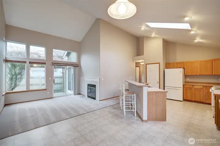 Looking from the large kitchen dining area towards the bright family room with gas fireplace and slider to the fenced backyard and patio.