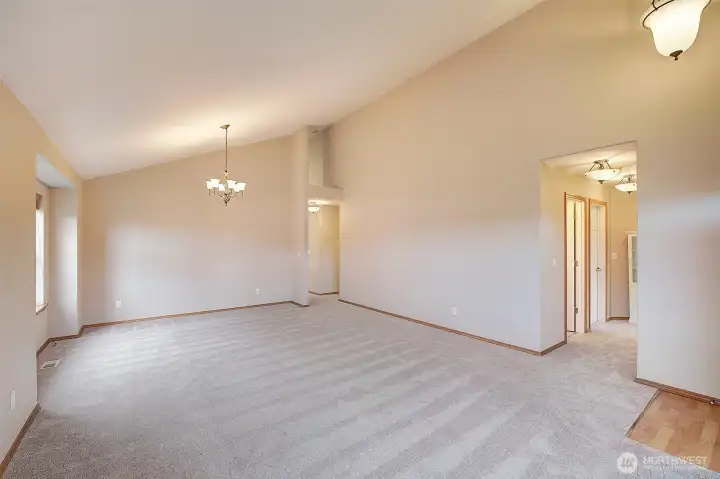 Living room looking towards the hallway on the right leads to the 2 front closets on the right and the main bath on the left of the hall. Bedrooms 2 and 3 are just down the hall. The hallway at the back of the room leads straight through to the kitchen with dining space and family room. Primary suite and laundry room are down the shrt hal to the right.