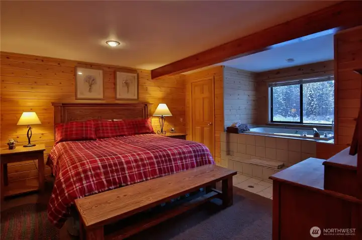 Lower-level ensuite bedroom offering warm wood finishes, private bath access, and a peaceful retreat for guests.