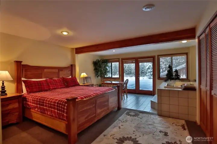 Expansive bedroom with ensuite soaking tub, natural light, and access to the outdoors for a true retreat experience