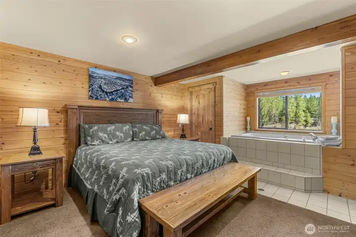 Lower-level ensuite bedroom offering warm wood finishes, private bath access, and a peaceful retreat for guests.