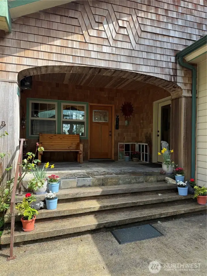 Entrance to this one-of-a-kind home. Stone steps and deck grace the entrance.