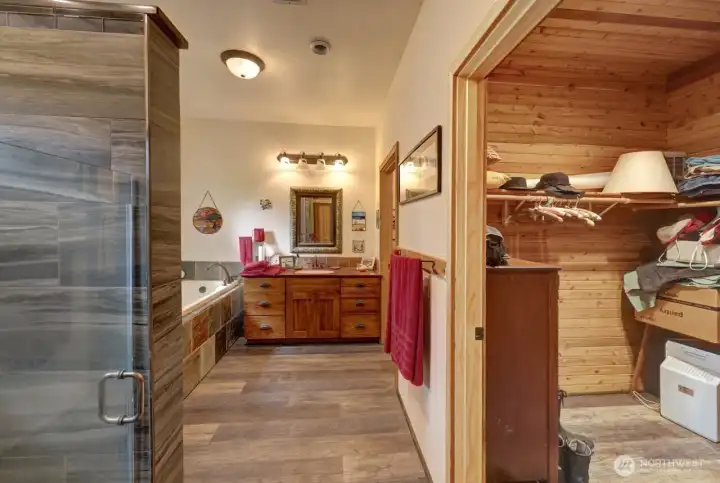 Large tile shower, walk in closet opposite one of the two individual sinks and custom cabinets.