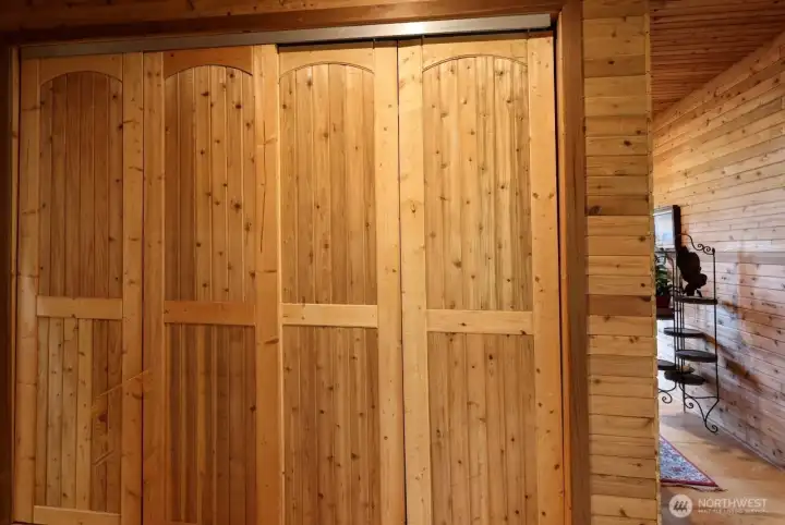 In the hallway of the Primary Suites is a bank of closet doors. and a peek at the primary bedroom.