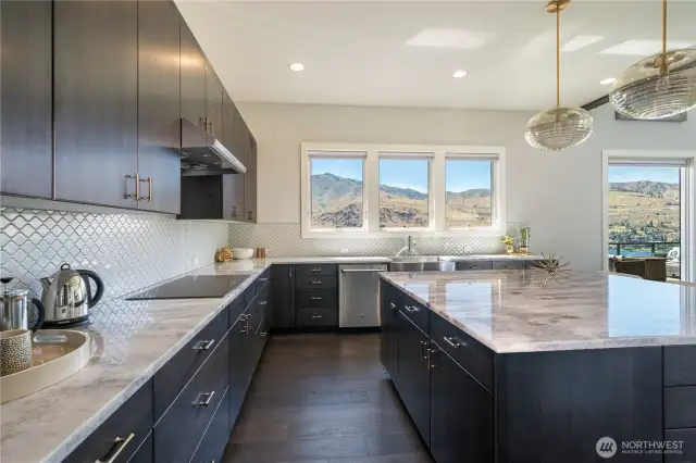 The views from the kitchen sink makes anyone happy to do the dishes! Smoke black white oak cabinets and imported marble natural stone counters throughout this spacious kitchen. Note the induction cook top and large drawers for pots and pans. All the lower cupboards have pullouts, too!