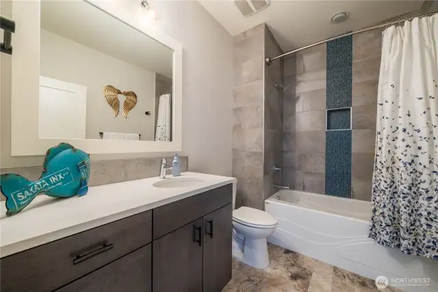 Main bathroom downstairs with a tub shower combination. Large tub, ceiling high tiles and vinyl tile floors make this bathroom more durable for your rough and tumble house guests! Lots of storage here, too!