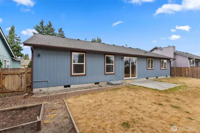 Fenced backyard with patio, raised garden beds and garden shed.
