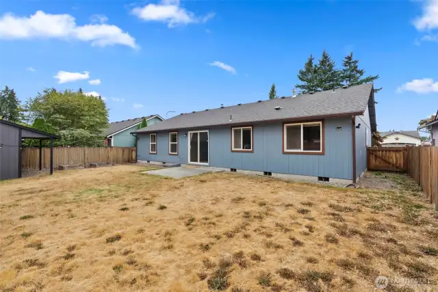 Fenced backyard with patio, raised garden beds and garden shed.