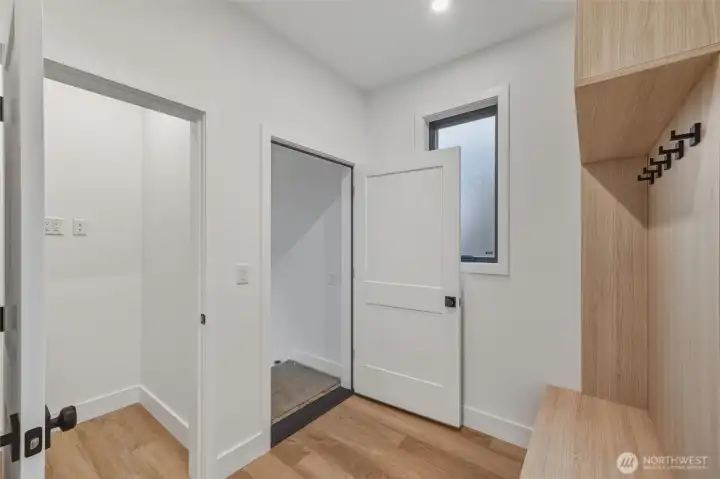 A view of the mud room area with built in shelving and under stair storage closet, just off the garage entrance.