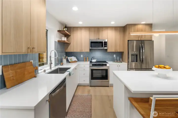 Beautiful white quartz countertops, two tone cabinets with full tiled backsplash and stainless steel appliances
