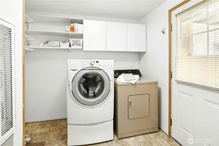 Laundry with ample storage and door to carport