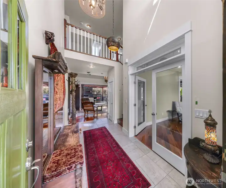 Grand entry with vaulted ceilings and custom lighting above, a peek a boo of the catwalk on second floor adds architectural surprise. Secondary living space or office/bonus room located on the right through French doors