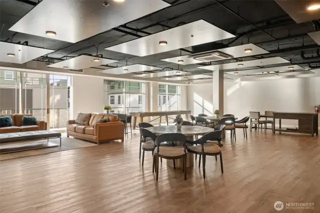 Ample seating throughout creates a welcoming atmosphere, complemented by a shuffleboard table and movable ping pong table for added fun and direct access to a deck offering partial water views