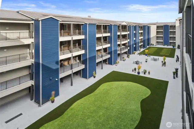 Fifth-floor community courtyard with a putting green, bocce ball, fire-pit and seating.