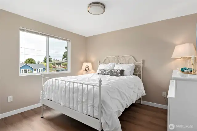 The guest bedroom boasts a fresh new look with updated flooring, a new window with blinds, fresh paint, and a modern light fixture—making it bright, comfortable, and welcoming for visitors.