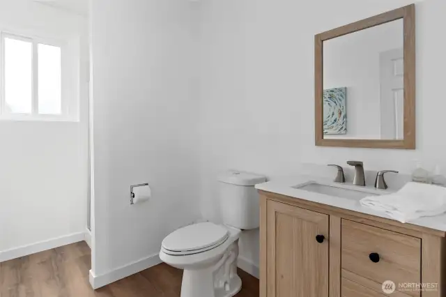 The lower-level bathroom shines with new flooring, fresh paint, an updated toilet and vanity, plus a new window that fills the space with natural light—bright, clean, and ready to impress.
