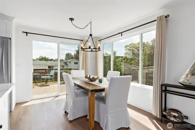 The dining room is filled with natural light and features stylish new light fixtures, updated windows with fresh coverings, beautiful new flooring, and a sliding door that opens to the great outdoors—perfect for seamless indoor-outdoor living.
