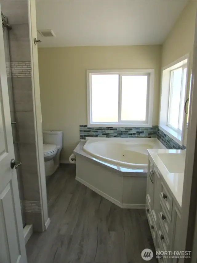 JETTED TUB IN CORNED, GLASS TILE ACCENT WALL TRIM.