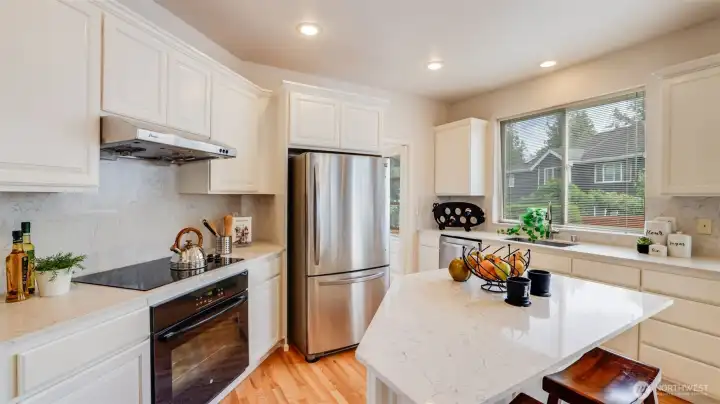 Recently updated kitchen is bright and inviting for meal time or entertaining boasting newly painted cabinets, countertops and backsplash, and an island with seating for quick meals.