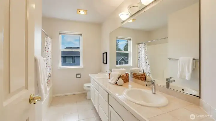 This full guest bathroom is perfect for any use, featuring a connected shower and tub, a polished finish, and a double vanity for added convenience