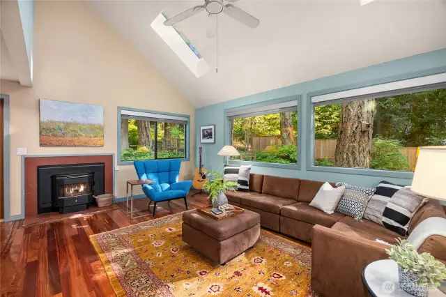 Adjacent to the entry is the living room, featuring vaulted ceilings, skylights, rich hardwoods and large windows bringing the outdoors in