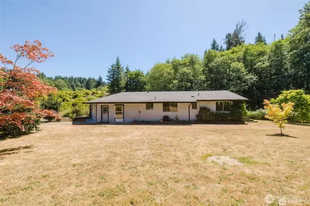 Beautiful level area with decorative trees lined with fence or fruit bearing blackberry bushes.