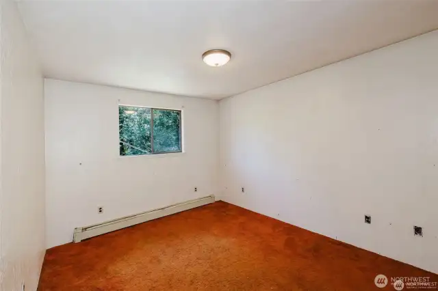 one of the auxiliary bedrooms on the other side of the hall from primary. Window overlooks the deck and stream