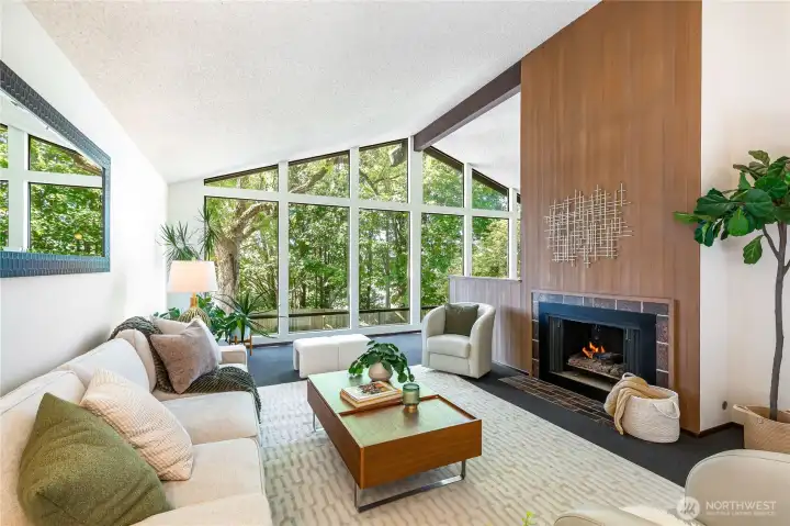 A dramatic entrance opens to soaring ceilings and a double-sided fireplace, with a wall of glass framing woodland privacy and seasonal light.”