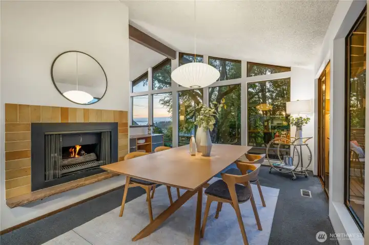 Dining area anchored by the home’s double-sided fireplace, balancing warmth and function with treetop and Sound views beyond.