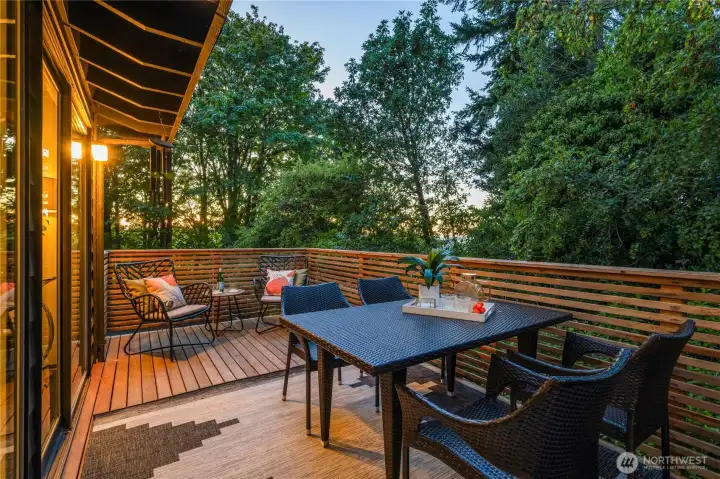 Lanai dining deck, approx. 12 by 7 feet, extends seamlessly from the dining room, offering a woodland-wrapped space for meals and gatherings.