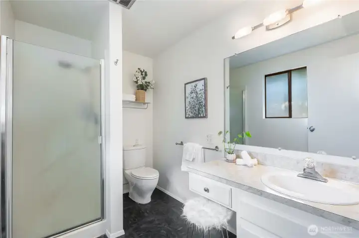 Primary en suite bath with step-in shower and wide vanity, bringing function and light to the home’s private wing.”